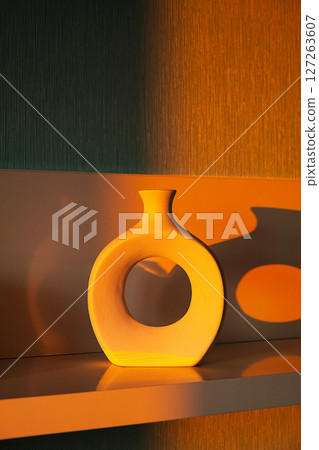Donut Shape Ceramic Vase with Warm Sunset Light and Shadow on Modern Shelf. Home Decor and Minimal Design Concept. 127263607