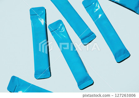 Blue Foil Sachets are Scattered on Light Blue Background. Packaging for Single Serving Products. Food and Beverage Industry. 127263806