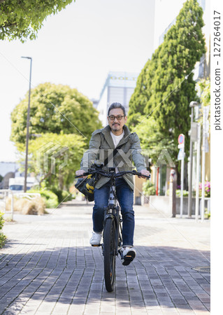 A man in his late 50s riding a bicycle 127264017