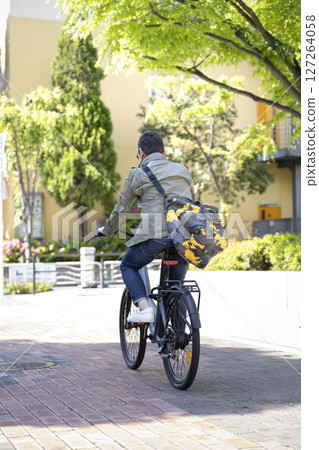 Rear view of a man in his late 50s riding a bicycle Rear view of a man in his late 50s riding a bicycle 127264058