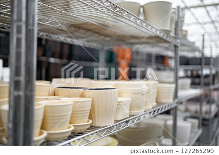 Shelves in a plant shop displaying various flowerpots in different sizes and designs, all ready for sale. Shelves in a plant shop displaying various flowerpots in different sizes and designs, all ready for sale. 127265290
