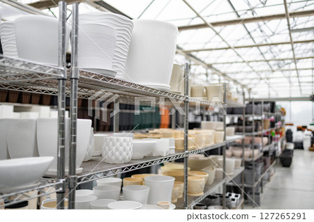 A collection of flowerpots displayed on shelves inside of a plant shop, showing variety in shape and size. A collection of flowerpots displayed on shelves inside of a plant shop, showing variety in shape and size. 127265291