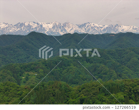 A view of the fresh greenery of the countryside and the remaining snow on the Hakuba Sanzan mountains from the Alps Observatory, Ogawa Village, Nagano Prefecture (aerial photography by drone) 127266519