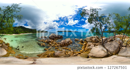 A rocky shoreline with transparent, shallow waters surrounded by lush greenery, overlooking distant islands. Praslin, Seychelles. Smoon Island. 360 Degree view. A rocky shoreline with transparent, shallow waters surrounded by lush greenery, overlooking distant islands. Praslin, Seychelles. Smoon Island. 360 Degree view. 127267501