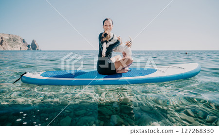 Woman Paddleboard Yoga Ocean - Woman practicing yoga on a paddleboard in the ocean, showcasing a tranquil and healthy lifestyle. 127268330