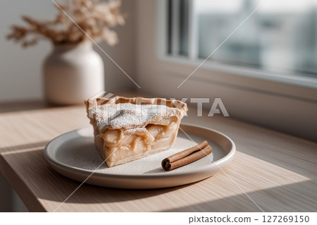 Delicious Slice of Apple Pie Decorated with Powdered Sugar and Cinnamon on a White Plate 127269150