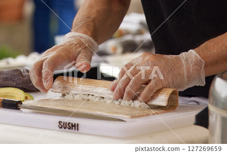 Chefs Hands Preparing Sushi Roll With Bamboo Mat at Asian Cuisine Event Chefs Hands Preparing Sushi Roll With Bamboo Mat at Asian Cuisine Event 127269659