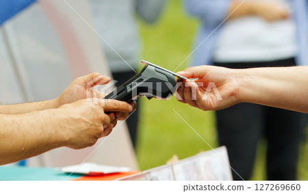 Person Making a Contactless Payment Using a Card Reader Outdoors 127269660