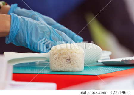 Gloved hands preparing rice with spatula, onigiri 127269661
