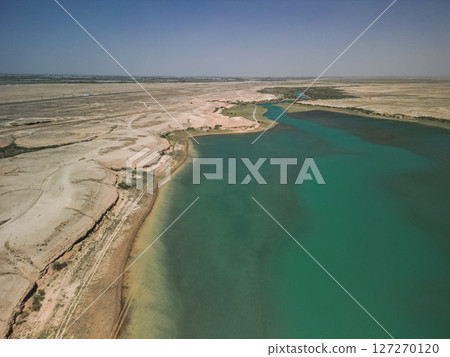 Aerial view of winding Kuimazar Reservoir shoreline in arid Uzbekistan landscape Aerial view of winding Kuimazar Reservoir shoreline in arid Uzbekistan landscape 127270120