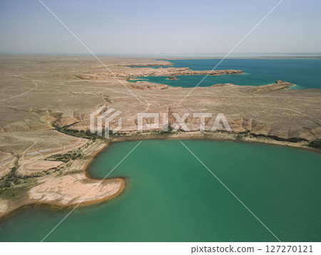 Turquoise water and desert peninsula at reservoir in Uzbekistan panoramic scene Turquoise water and desert peninsula at reservoir in Uzbekistan panoramic scene 127270121