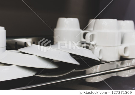 Kitchen utensil. White cutlery. Clean plates and cups on metal table. Kitchenware isolated. White dishes and mugs. Restaurant porcelain cutlery. Kitchen interior. Kitchen utensil. White cutlery. Clean plates and cups on metal table. Kitchenware isolated. White dishes and mugs. Restaurant porcelain cutlery. Kitchen interior. 127271509