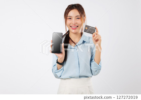 Asian woman show card, credit, phone screen, payment on smartphone while shopping. Smiling female holds a phone and a credit card on a white background, buy with card. isolated studio white background 127272019