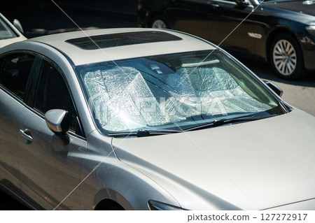 Protective reflective surface under windshield of passenger car parked on hot day. Summertime Protective reflective surface under windshield of passenger car parked on hot day. Summertime 127272917