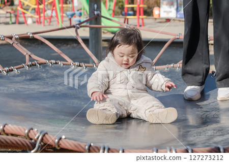 [A one-year-old child playing with his mother on the trampoline in the children's playground at Sagamihara City Asamizo Park] 127273212