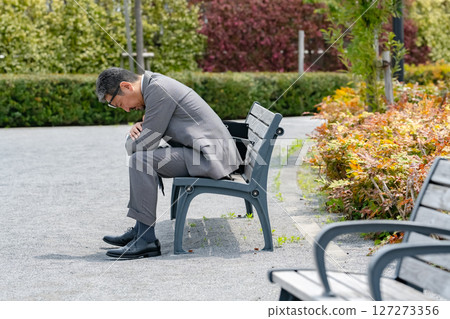 Worried businessman sitting on a bench 127273356