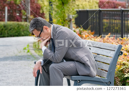 Worried businessman sitting on a bench Worried businessman sitting on a bench 127273361