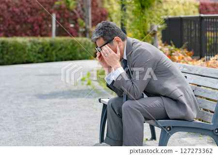 Worried businessman sitting on a bench 127273362