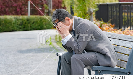 Worried businessman sitting on a bench 127273363