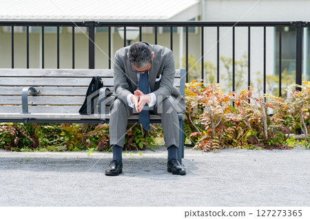 Worried businessman sitting on a bench 127273365