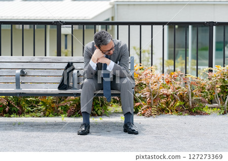 Worried businessman sitting on a bench Worried businessman sitting on a bench 127273369