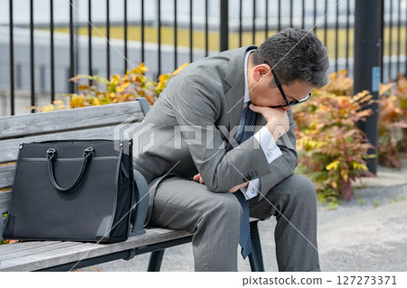 Worried businessman sitting on a bench 127273371