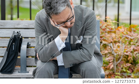 Worried businessman sitting on a bench 127273373