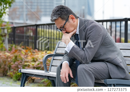 Worried businessman sitting on a bench Worried businessman sitting on a bench 127273375