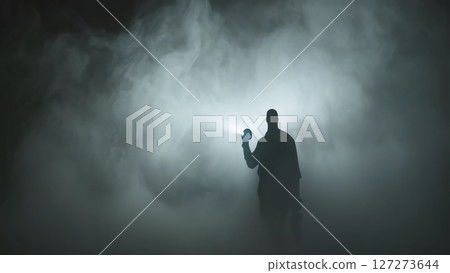 A person holding a flashlight shining light into the fog A person holding a flashlight shining light into the fog 127273644