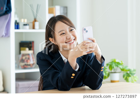 一名高中女生在房間裡看著她的智慧型手機 127273897