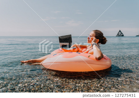 Woman Laptop Beach Working on Laptop While Floating on a Pool Float in the Ocean Woman Laptop Beach Working on Laptop While Floating on a Pool Float in the Ocean 127275431