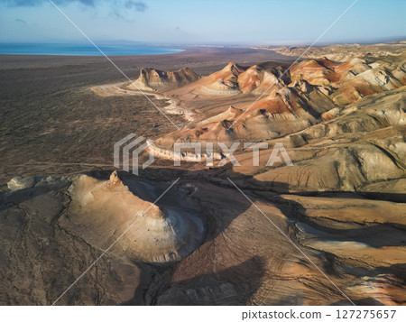 Golden sunrise colors illuminate Aktumsik Cape's curved formations, dry ravines 127275657