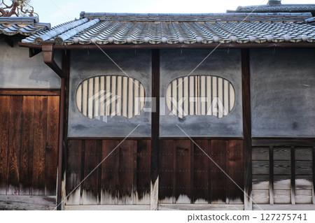 Takehara, Hiroshima Prefecture - A traditional Japanese house with a blue plaster wall and a unique circular lattice window design Takehara, Hiroshima Prefecture - A traditional Japanese house with a blue plaster wall and a unique circular lattice window design 127275741