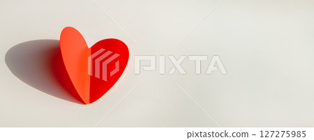 Banner with paper decoration in the shape of a red heart on a white background. Flat plan, top view, space for text on the right side 127275985