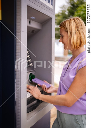 Visiting an ATM in sunny Greece during summer days 127277785