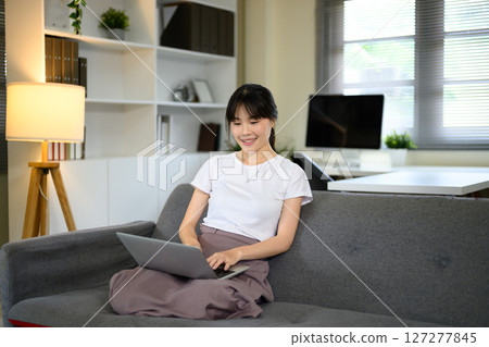 Young woman relaxing with laptop computer in living room 127277845