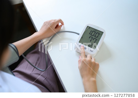 Closeup woman check up low blood pressure with digital pressure monitor, Hypotension problem 127277858