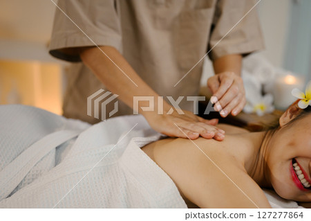 Closeup relaxed woman lying on massage table while massage therapist massages her 127277864