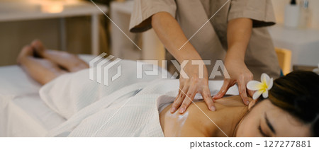 Closeup relaxed woman lying on massage table while massage therapist massages her Closeup relaxed woman lying on massage table while massage therapist massages her 127277881