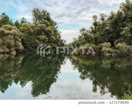 A calm lake with trees in the background 127279040