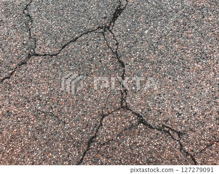 A cracked and broken road with a lot of gravel A cracked and broken road with a lot of gravel 127279091