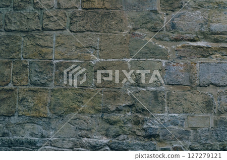 A wall made of stone bricks with a rough texture 127279121