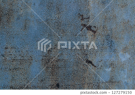 A blue and rusted wall with a lot of cracks and holes 127279150