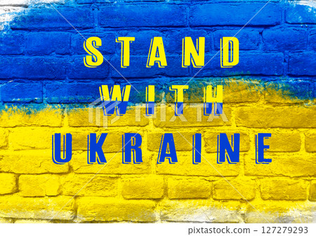 A blue and yellow brick wall with the words Stand with Ukraine written on it 127279293