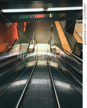 Long silver escalator with a red stripe down the middle 127279367