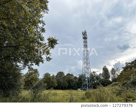 Tall tower is in the middle of a field with trees in the background 127279376