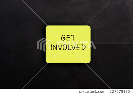 Yellow sign that says Get Involved is on a black background 127279380