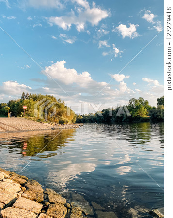 Calm body of water with a few trees in the background Calm body of water with a few trees in the background 127279418