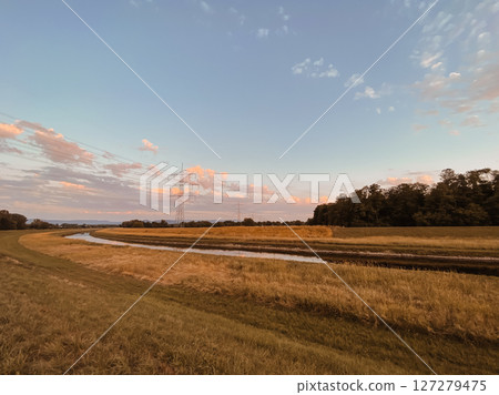 Field with a power line and a body of water Field with a power line and a body of water 127279475