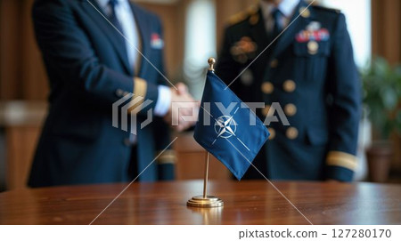 NATO flag with officers shaking hands in background 127280170